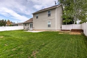 Lehi apartment for rent - the back of a house with a yard and a white fence