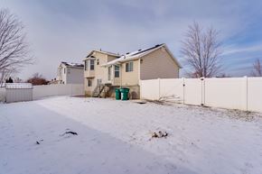 Layton apartment for rent - A house with a white fence and a green trash can in the snow.