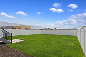 Eagle Mountain apartment for rent - A white fence surrounds a green lawn with a building in the background.