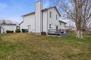 Kaysville apartment for rent - A house with a grey roof and a chimney is surrounded by a grassy area.