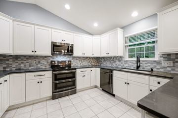 Milford apartment for rent - A kitchen with white cabinets and a black countertop.
