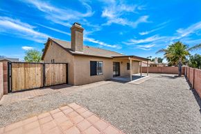 Tucson apartment for rent - A house with a brown roof and a chimney is surrounded by a gravel driveway and a wooden fence.