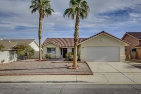 Henderson apartment for rent - A house with a red tile roof and a white garage door is surrounded by palm trees.