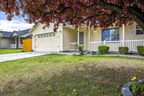 Nampa apartment for rent - a yellow house with a white garage door in front of a lawn