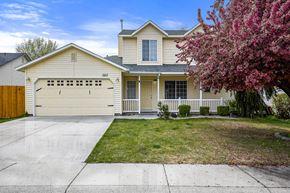 Nampa apartment for rent - a yellow house with a white garage door and a lawn