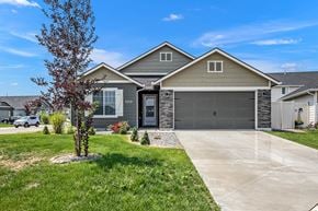 Nampa apartment for rent - A house with a grey garage door and a tree in front.