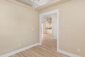Boise apartment for rent - A room with light wood flooring and white walls leading to another room.