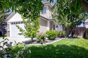 Nampa apartment for rent - A house with a white garage door and a tree in front of it.