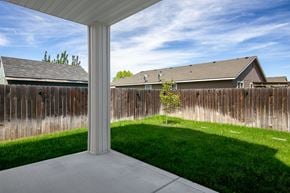 Nampa apartment for rent - A white pillar stands in a concrete patio with a wooden fence and houses in the background.