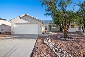 Tucson apartment for rent - A house with a white garage door and a tree in front.