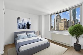 New York apartment for rent - A bedroom with a large bed and a city view through the window.