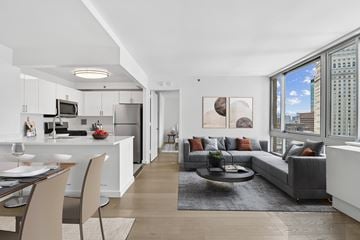 New York apartment for rent - A modern living room with a grey couch and a dining table.