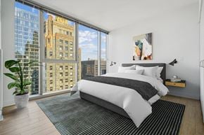 Chicago apartment for rent - a bedroom with a large window and a bed and a rug