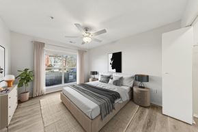 Chapel Hill apartment for rent - A bedroom with a large bed, a ceiling fan, and a window with a view of a backyard.