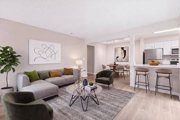 Tampa apartment for rent - A modern living room with a grey sofa, green armchair, and a coffee table with a lamp on it.