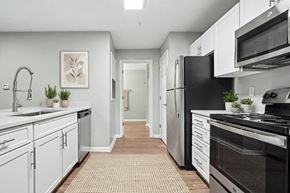 Charlotte apartment for rent - A kitchen with white cabinets and black appliances.