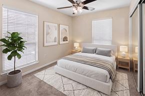 Austin apartment for rent - A bedroom with a large bed, a ceiling fan, and a potted plant.