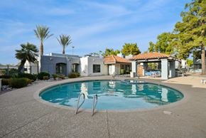 Chandler apartment for rent - A swimming pool in a backyard with a house and palm trees in the background.