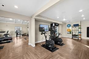 Chandler apartment for rent - A spacious home gym with wooden floors and a variety of exercise equipment.