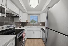 Chandler apartment for rent - A kitchen with white cabinets and black appliances.
