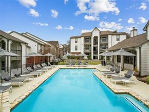 Austin apartment for rent - a swimming pool with chairs and umbrellas next to a building