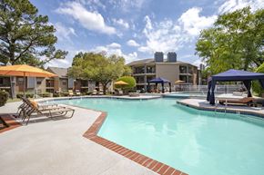Charlotte apartment for rent - A large swimming pool with a red brick border and a blue canopy.