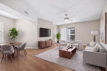 Charlotte apartment for rent - A living room with a grey couch, a wooden coffee table, a television, and a dining table with chairs.