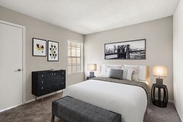 Charlotte apartment for rent - A bedroom with a large bed, a bench, and two lamps.