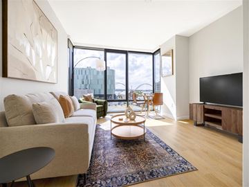 Washington apartment for rent - a living room with a couch and a tv and a balcony