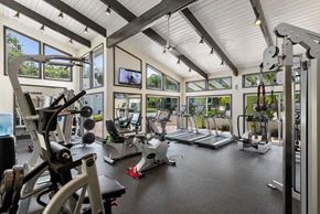 West Palm Beach apartment for rent - A spacious and light filled fitness center with a variety of equipment and a television mounted on the wall.