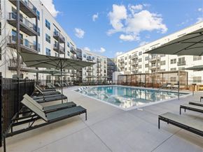 Atlanta apartment for rent - a swimming pool with benches and umbrellas in front of an apartment building