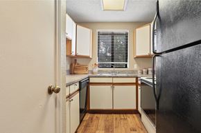 Garland apartment for rent - A kitchen with a black refrigerator and wooden floors.