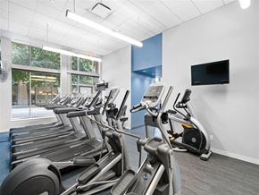 Cambridge apartment for rent - A row of treadmills in a gym with a TV mounted on the wall.