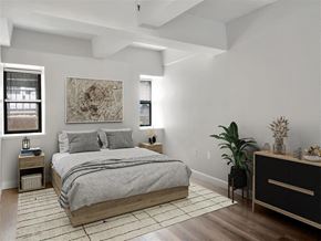 Cambridge apartment for rent - A bedroom with a large bed and a painting on the wall above the bed, two windows on either side of the bed..