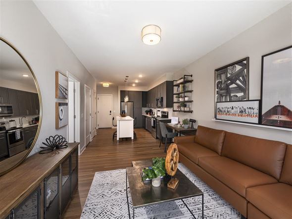Baltimore apartment for rent - A modern living room with a brown leather couch and a coffee table in the center.