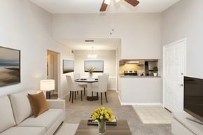 Raleigh apartment for rent - A living room with a white couch, a dining table, and a television.
