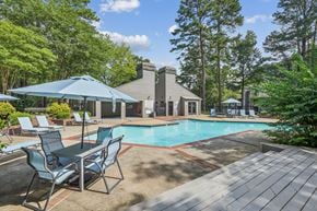 Raleigh apartment for rent - A pool surrounded by trees and chairs.