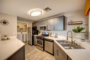 Las Vegas apartment for rent - A kitchen with a stove top oven, microwave and a refrigerator.  The laundry room is in the background.