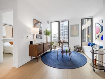 Bronx apartment for rent - A living room with a blue rug and a wooden chair.