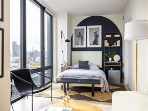 Bronx apartment for rent - A black and white bedroom with a large bed and a chair.