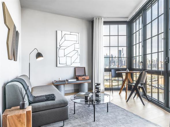 Brooklyn apartment for rent - a living room with a couch and a desk in front of large windows