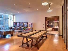 New York apartment for rent - a games room with a row of pinball machines and a table