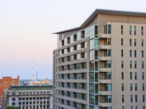 Dallas apartment for rent - A tall building with many windows is in the foreground with a building and crane in the background.
