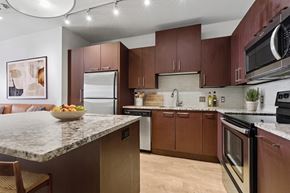 Dallas apartment for rent - A kitchen with brown cabinets and a marble countertop.