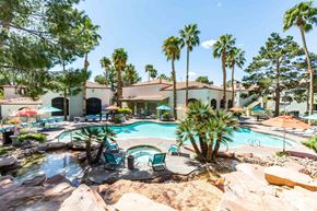 Las Vegas apartment for rent - a swimming pool with palm trees and chairs around it