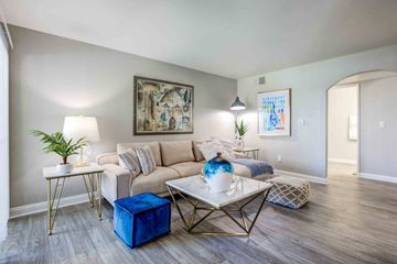 Las Vegas apartment for rent - A living room with a white couch, a blue ottoman, and a painting on the wall.