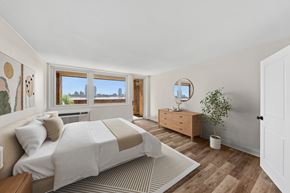 New York apartment for rent - A bedroom with a large bed and a window overlooking a cityscape.