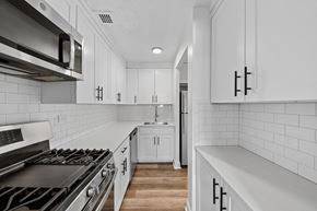 New York apartment for rent - A modern kitchen with white cabinets and a black stove top.