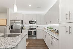 Charlotte apartment for rent - a white kitchen with marble counter tops and stainless steel appliances and plank-style florring