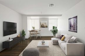 Dallas apartment for rent - A modern living room with a grey sofa, a coffee table, and a flat-screen TV mounted on the wall.